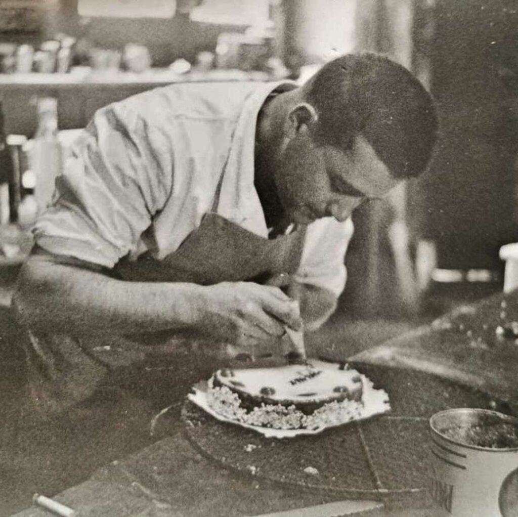 photo vintage pâtissier qui écrit avec un cornet de chocolat